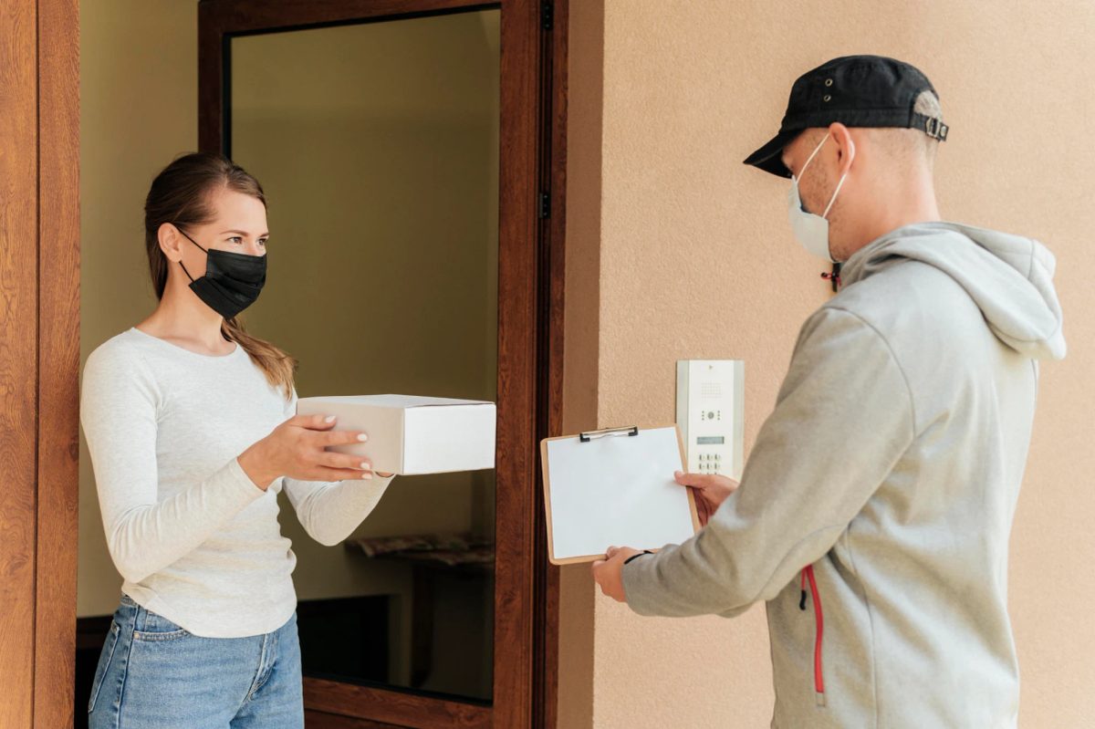 Home seller handing over an order at the door during a scheduled collection slot, with no signage displayed